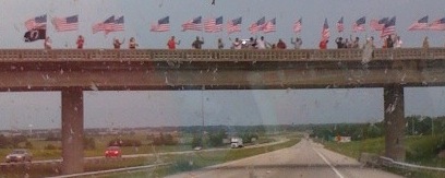 Cropped group of people flying the American flag on a highway bridge